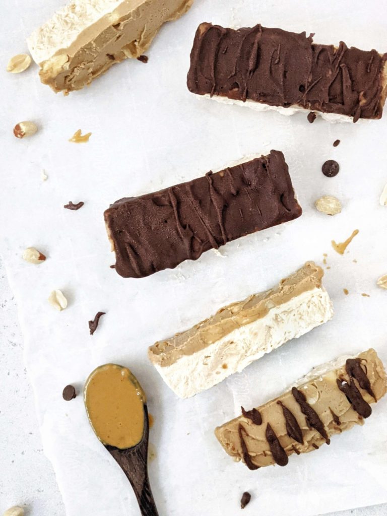 Homemade Protein Snickers Ice Cream bars made with Greek Yogurt and Protein Powder! With layers of peanut butter protein ice cream, sugar free peanut butter caramel, chopped peanuts and chocolate, it’s like eating a healthy protein snickers candy bar as ice cream!