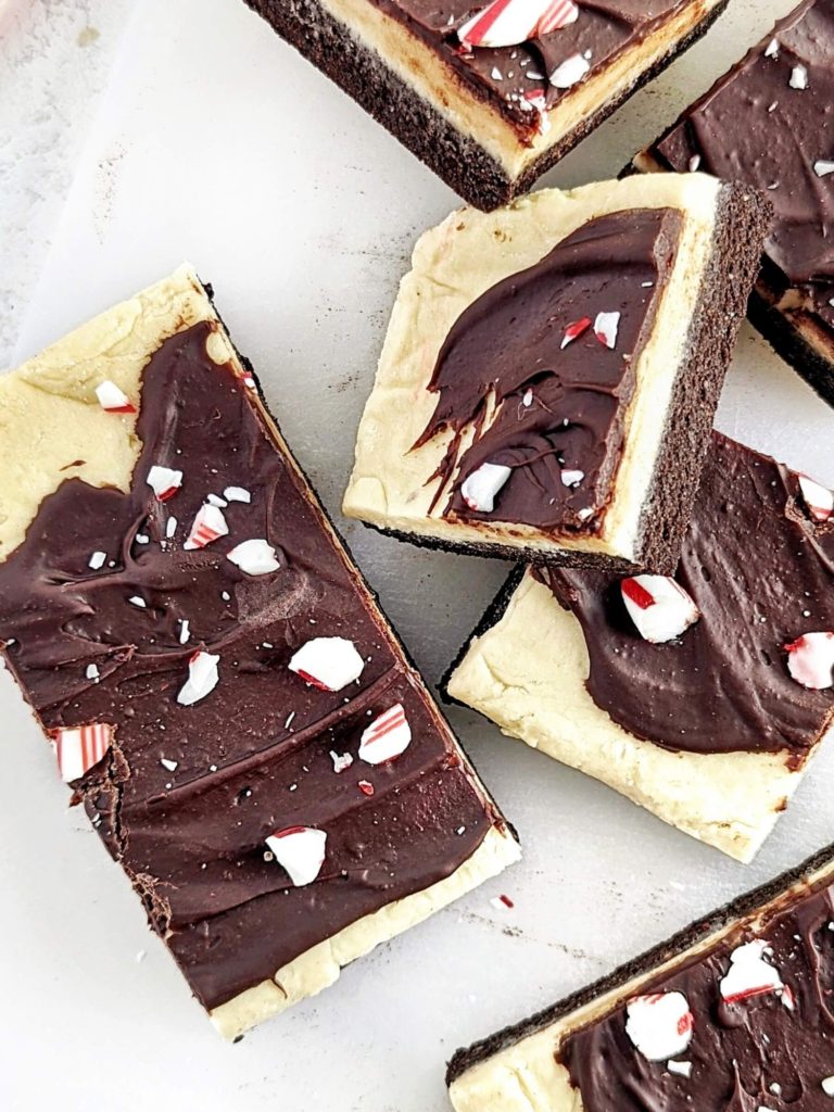 Layered Peppermint Bark Protein Bars with the chocolate peppermint base, thick frosting and chocolate topping - but all sugar free! Healthy, no bake peppermint bars use protein powder instead, as well as oat flour and Greek yogurt.