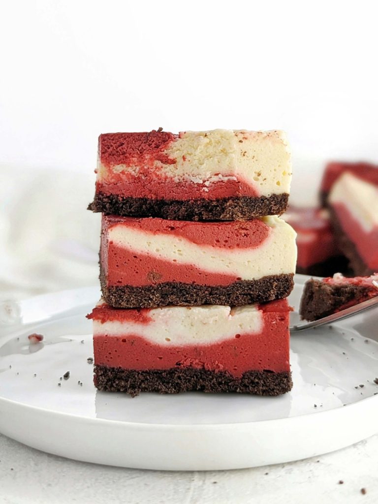 Unbelievably amazing Protein Red Velvet Cheesecake with swirls of red velvet and regular cheesecake batters. Healthy red velvet cheesecake bars are low fat, low carb and have no sugar added!