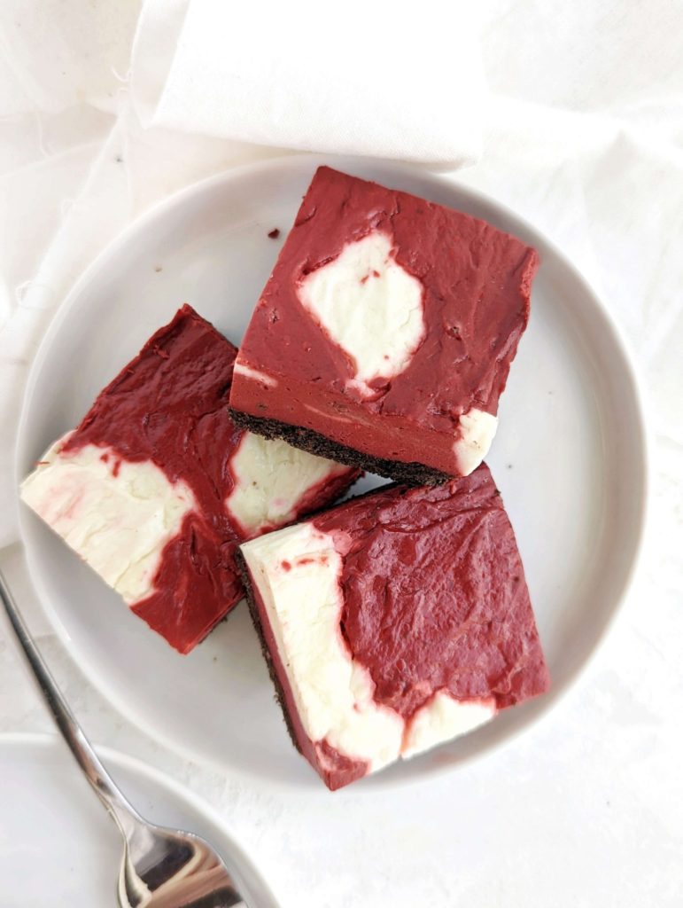 Unbelievably amazing Protein Red Velvet Cheesecake with swirls of red velvet and regular cheesecake batters. Healthy red velvet cheesecake bars are low fat, low carb and have no sugar added!
