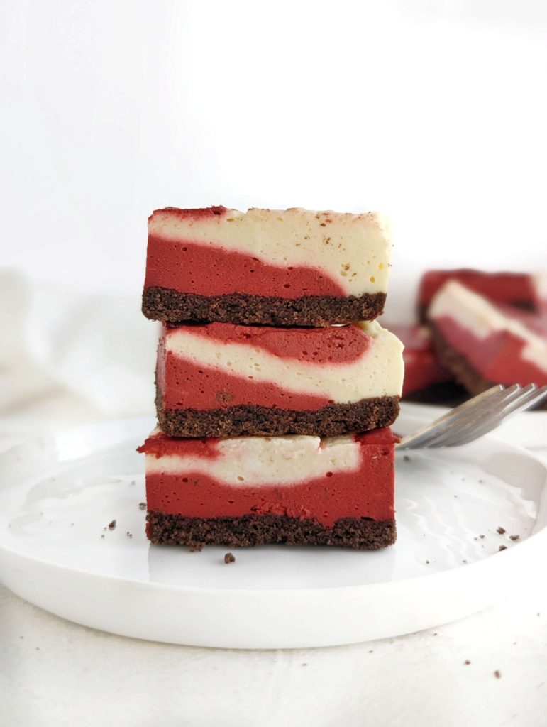 Unbelievably amazing Protein Red Velvet Cheesecake with swirls of red velvet and regular cheesecake batters. Healthy red velvet cheesecake bars are low fat, low carb and have no sugar added!