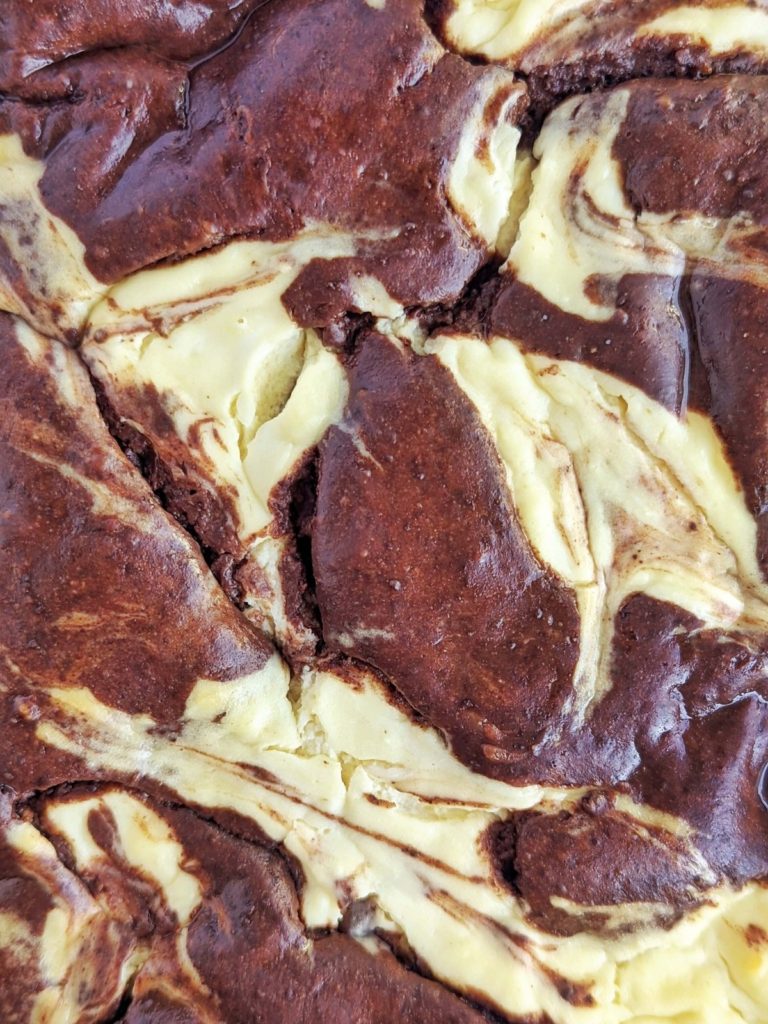 Super good Protein Cheesecake Brownies with swirls of brownie and cheesecake! These healthy cream cheese brownies are made with protein powder, monk fruit and Greek yogurt for a sugar free and butter-free dessert!