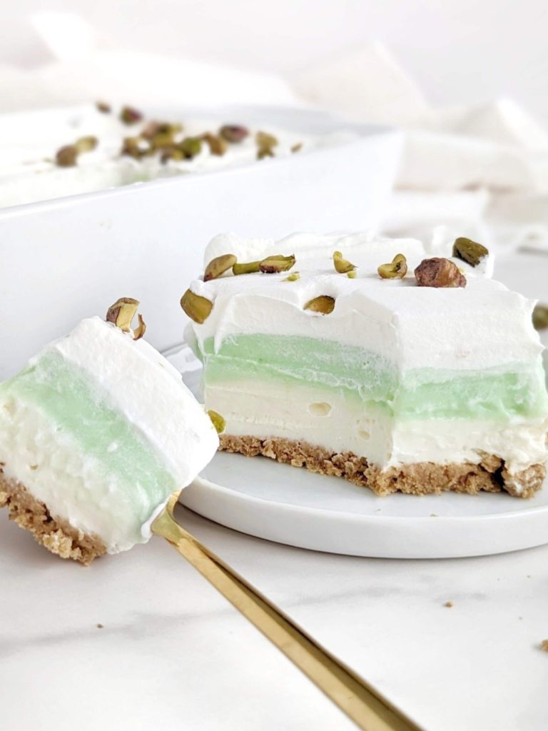 Superb Healthy Pistachio Pudding Dessert with layers of low-fat graham cracker base, high protein cheesecake and pistachio pudding, and whipped topping! Layered pistachio dessert lasagna uses protein powder for a low sugar treat.