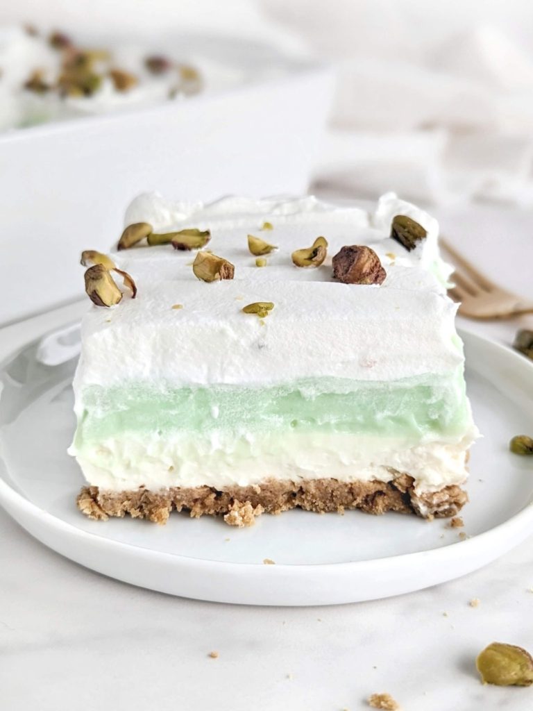 Superb Healthy Pistachio Pudding Dessert with layers of low-fat graham cracker base, high protein cheesecake and pistachio pudding, and whipped topping! Layered pistachio dessert lasagna uses protein powder for a low sugar treat.