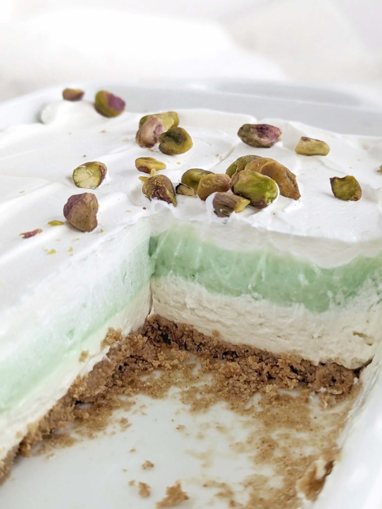 Superb Healthy Pistachio Pudding Dessert with layers of low-fat graham cracker base, high protein cheesecake and pistachio pudding, and whipped topping! Layered pistachio dessert lasagna uses protein powder for a low sugar treat.