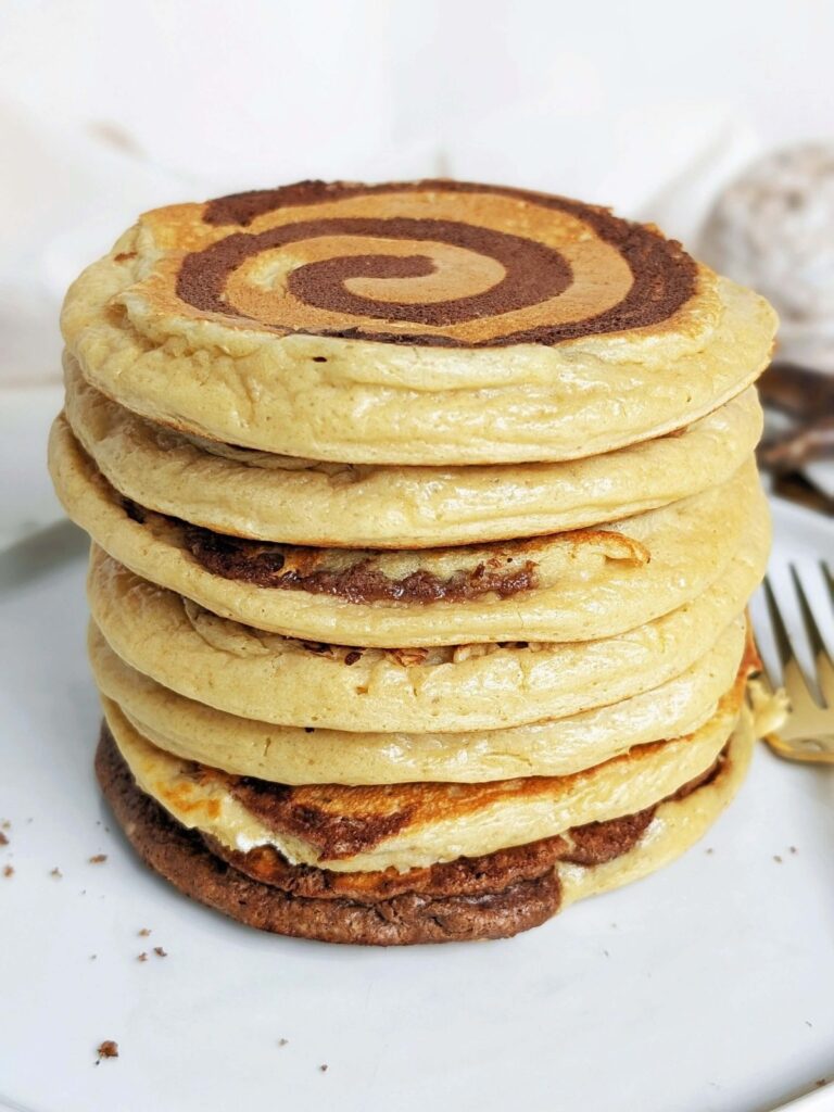 Perfect Cinnamon Roll Protein Pancakes complete with a cinnamon swirl! Cinnamon bun pancakes healthy and sugar free with protein powder and a protein shake.