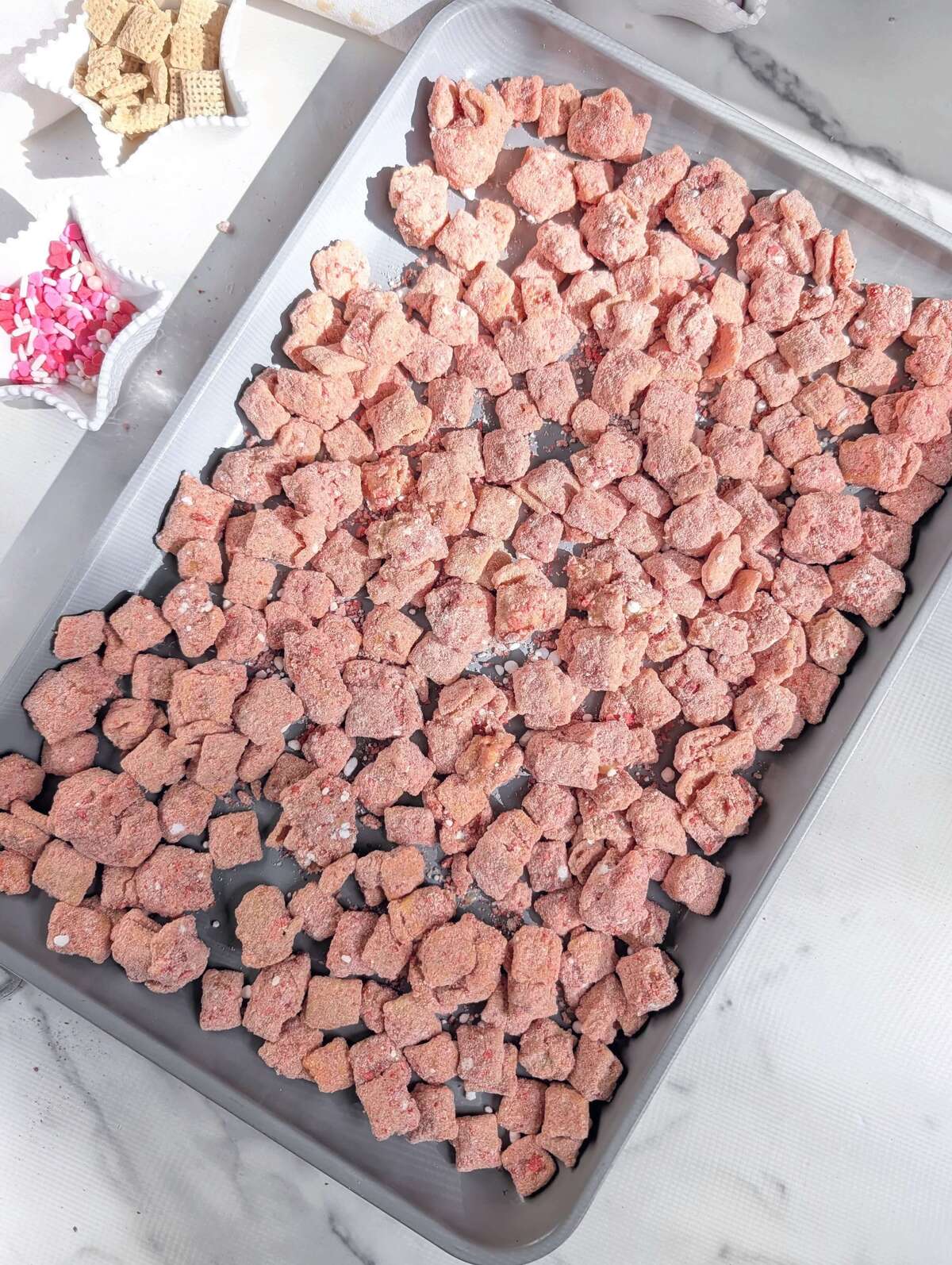 A healthy Valentine's Day Muddy Buddies recipe made with protein powder and naturally colored with freeze-dried strawberries. This Pink Puppy Chow is the perfect sweet, high-protein snack without the red food dye.